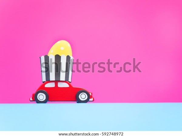 Small\
toy car delivery with easter egg on pink\
background