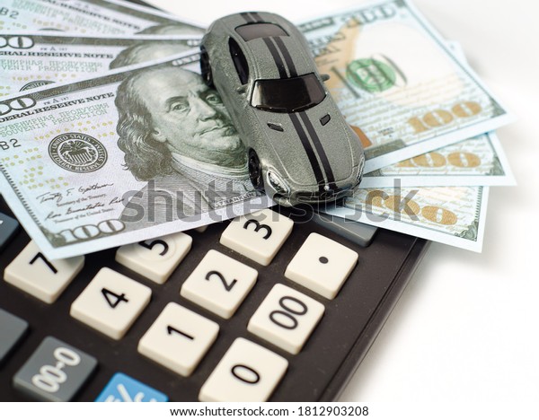 A small\
toy car stands on dollar bills and a calculator. Calculating the\
budget for buying a car. The accumulation of money to achieve the\
aims. August 23, 2020. Russia.\
Krasnoyarsk.