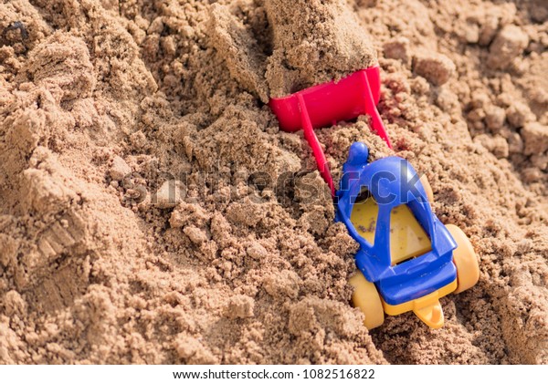 small toy digger working on sand quarry,\
construction concept