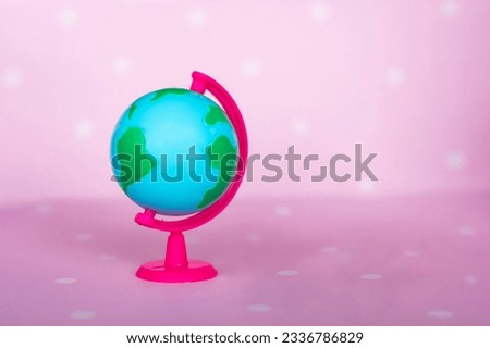 Small toy globe on a pink background. High quality photo