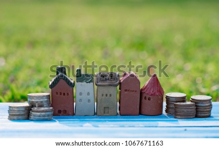 Small toy house and coins on wood floor with garden beakground for savemoney and real estate concept. Financial issue. 