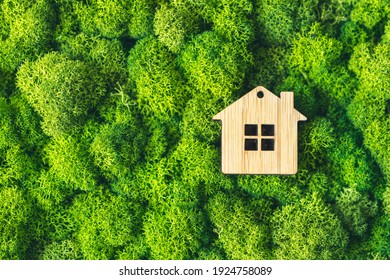 A small toy house on a background of plants as a symbol of a private country house. The concept of real estate in mortgages.