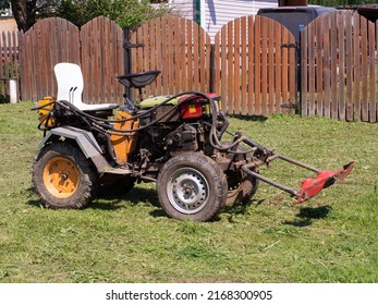 A Small Tractor With A Mower Attachment For Grass Standing On A Farm .agricultural Machinery.