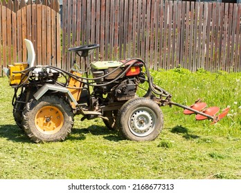 A Small Tractor With A Mower Attachment For Grass Standing On A Farm .agricultural Machinery.