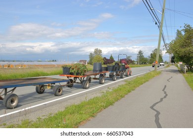 A Small Tractor Pulls Farm Equipment On A Road With Traffic./Farm Equipment On Road/A Small Tractor Pulls Farm Equipment On A Road With Traffic. 