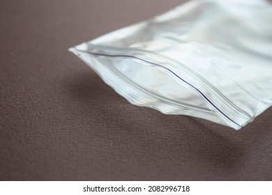 Small transparent plastic bag with zip clasp on a dark background. The clasp is open. - Shutterstock ID 2082996718