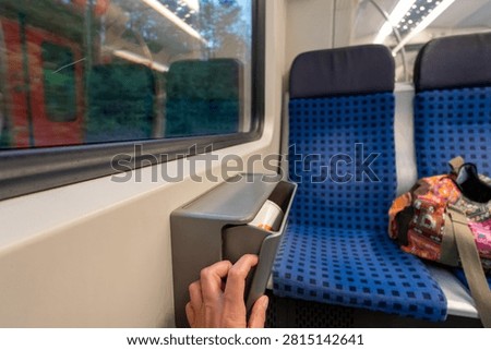 Small trash bin mounted between seats inside German S-Bahn train carriage. High quality photo