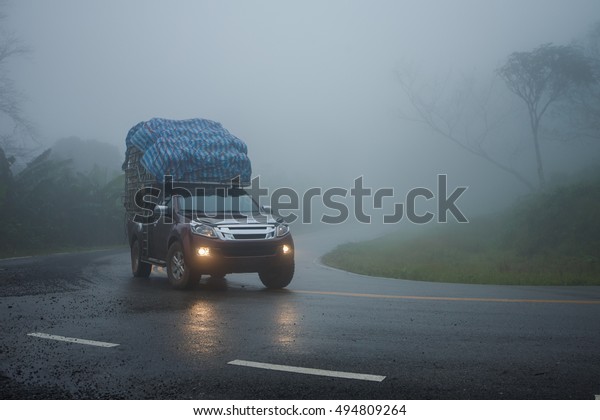 Small truck driving\
on the foggy \
road\
