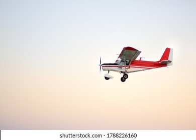 Small Ultralight Airplane With Overhead Wing And Single Propeller Flying In Sunset Sky. Such Aircraft Are Used For Recreational, Sport And Flight Training.