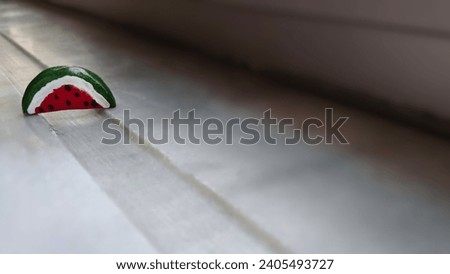 The small, upright pin in the shape of half a watermelon represents Palestine