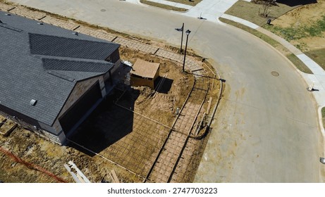 Small utility structure under assembly, rebar grids driveway framing at corner lot, Highpointe Ranch, US 377, Blackjack Rd home under construction. Shingle patterns, curved pavement, Aubrey, TX. USA