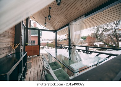 Small veranda with glass table and chairs in a scandi style wooden house. Vin is at home outside. Classic open terrace of a small log house