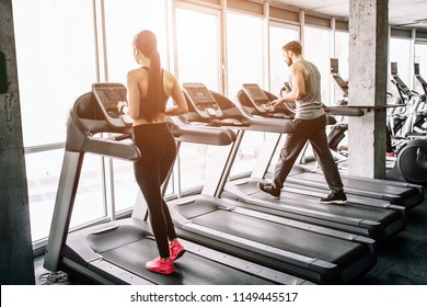 A Small View Of Big Sport Room Where Two People Are Having Workout. They Are Running On Elliptical Machines. The Exercise Is Intensive And Hard.