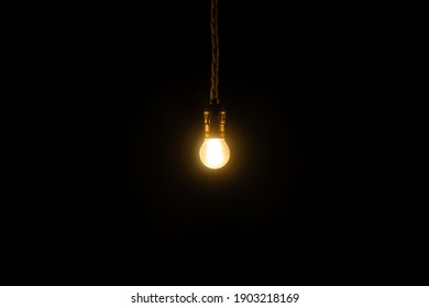 Small vintage glowing light bulb on black background. Electricity concept.
