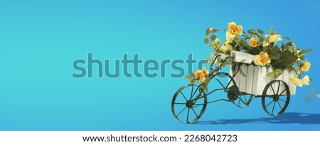 Small Vintage Tricycle Metal Planter with Flowers on Yellow and Turquoise Background and Text Space. Banner
