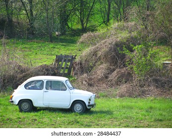 Small vintage white car parked near old wooden gate - Powered by Shutterstock