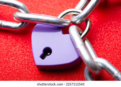 Small violet lock in shape of heart linked to the chain. Heart lock holding three pieces of chain. Concept of love