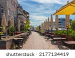 Small walkway in Ulm, Germany with tables and chairs under parasols, and traditional buldings on a sunny summer morning.