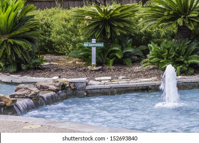A small waterfall and fountain sitting in front of a "No Swimming" sign.