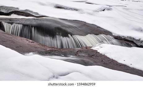 Small waterfall in the middle of a stream during the snowy Norwegian winter