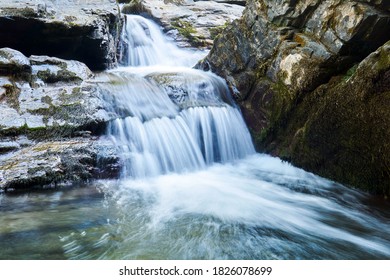 small waterfall in a mountain stream between rocks, water jets are blurred in motion