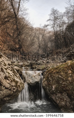 A small waterfall on a mountain small river in a beautiful autumn forest