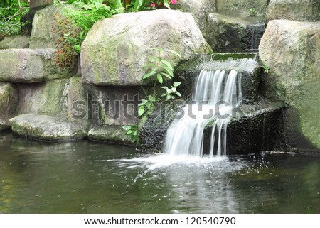 Small waterfall in public tropical garden.