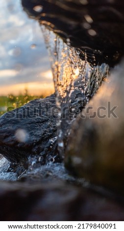 Small waterfall in the rays of the sunset of the spring sun
