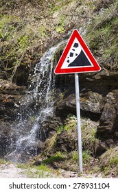 Small waterfall running behind a landslide sign outdoors