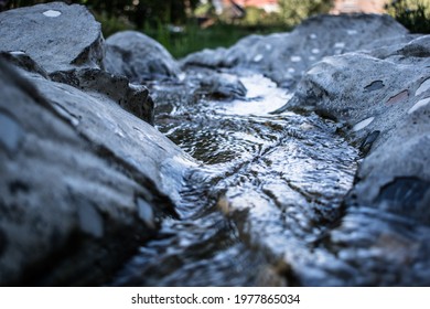 A small waterway flows peacefully between rocks. - Shutterstock ID 1977865034