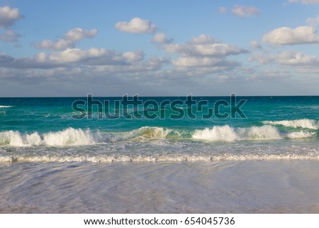 Small waves hitting the shore in the Caribbeans. Turquoise ocean and blue sky with cloud-stock photos