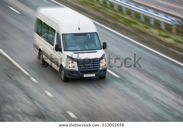 small white bus goes\
on highway in evening