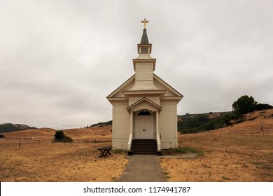 Small white church on dry brown grass in rural California