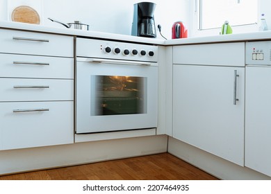 small white cozy and comfortable modern classic kitchen interior, with metal pan on electric stove, working oven, coffee maker on countertop. Mini kitchen for smart studio apartment - Shutterstock ID 2207464935