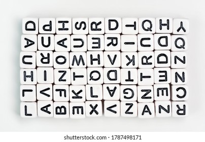 Small White Cube Beads With Various Letters Arranged In Rectangle, View From Above