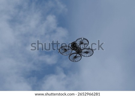 Small White FPV Drone with Propeller Guards Hovering in a Clear Blue Sky, Viewed from Below