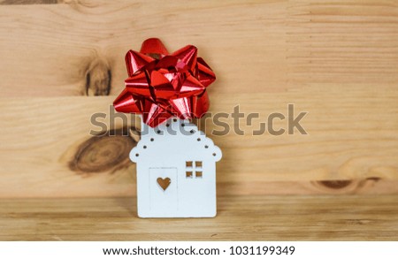 Small White House Model with Red Ribbon  On Wooden Background