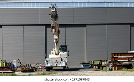 Small White Mobile Crane Outside The Steel Bars Manufacturing Factory. Front View.