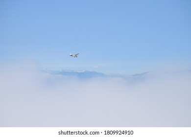 Small White Plane Flying Above The Clouds In The Mountain