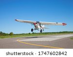 Small white single engine airplane takes off from a municipal airfield in rural Minnesota