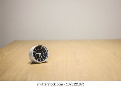 Small white table clock on a wooden table