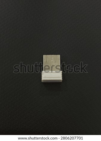 A small white USB wireless receiver dongle on a textured black background