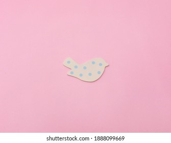 Small white wooden bird ornament with blue polka dots, top view on pink background - Powered by Shutterstock