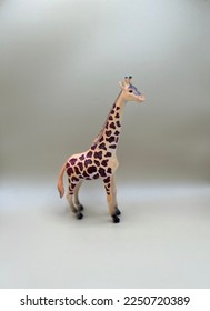 Small wild animal toy. Giraffe standing looking away to the side.