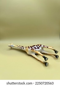 Small wild animal toy. Giraffe laying on the ground.
