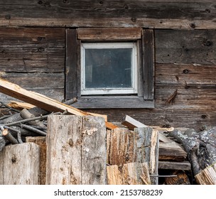 a small window on the wall of an old wooden house, old firewood stacked next to it. copy space.