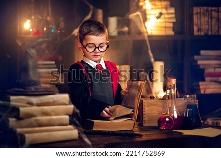 Small wizard in glasses reads magic book Cosplay. Halloween holiday. Halloween costume party. Decorate studio background