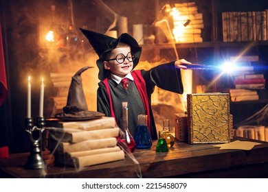 Small wizard in glasses and wizard's hat holding magic wand. Cosplay. Halloween holiday. Halloween costume party. Decorate studio background . - Shutterstock ID 2215458079