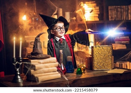 Small wizard in glasses and wizard's hat holding magic wand. Cosplay. Halloween holiday. Halloween costume party. Decorate studio background .