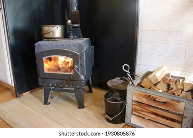 Small Wood Stove With Wood Fire Burning And Wood Bin On The Side